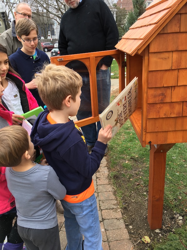Photo of children placing books in the Little Free LIbrary