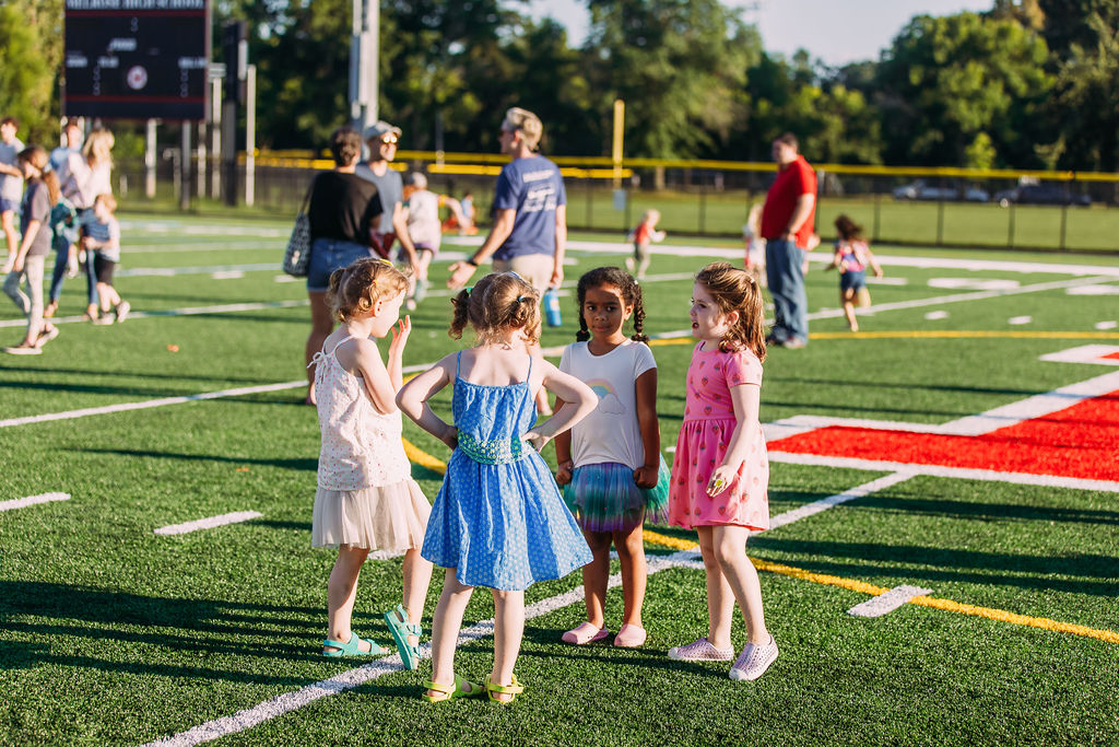 4 children standing in a circle on a football field talking