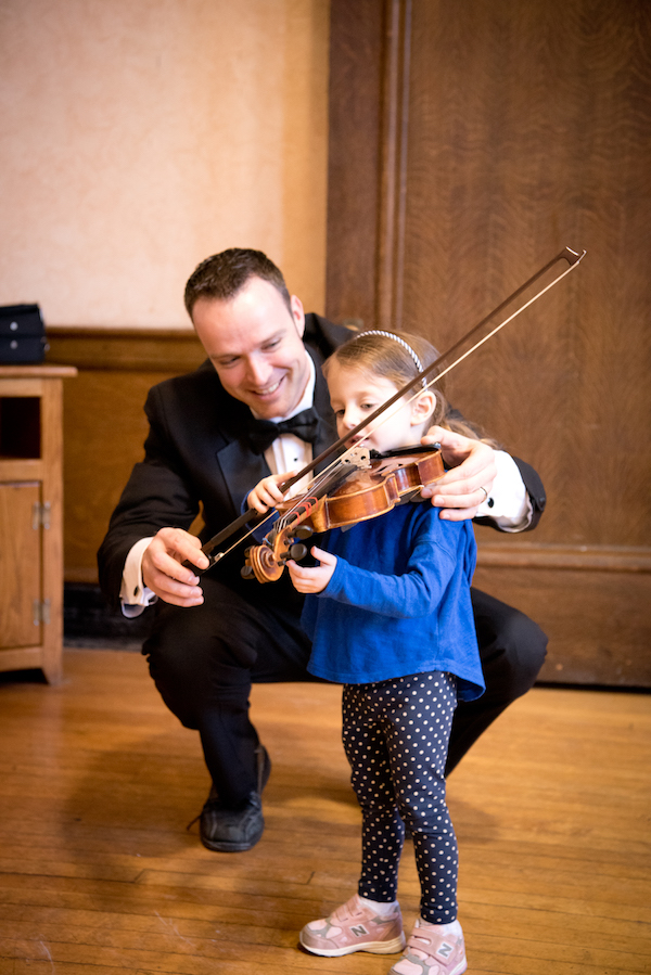 Musician showing a young girl how to play violin