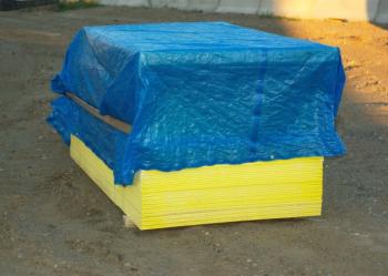 pallet of wood covered by blue plastic tarp