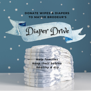Diapers on a white table against a blue and white polka dot background with banner that says Diaper Drive