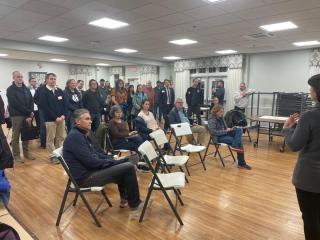 Community members sitting and standing during a public meeting.