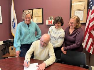 Mayor Brodeur Signs the order adopting the State's Specialized Energy Code surrounded by Staff.