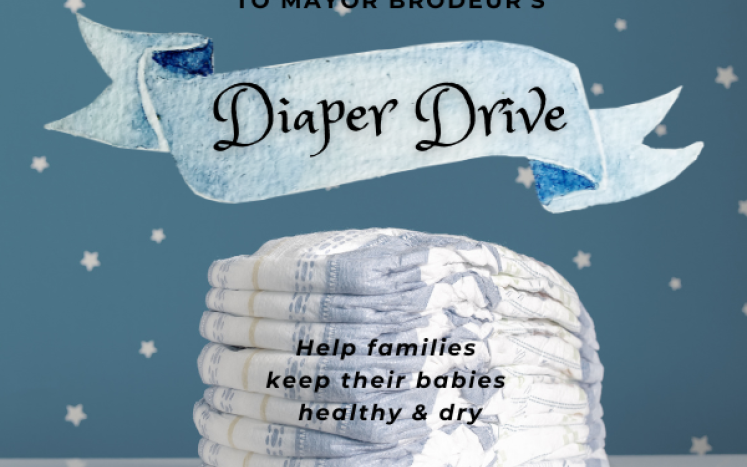 Diapers on a white table against a blue and white polka dot background with banner that says Diaper Drive
