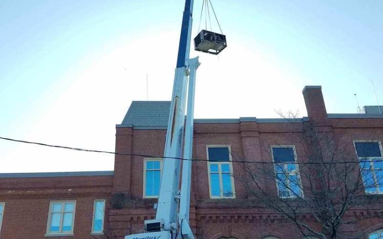 Energy-efficient rooftop unit being lifted to the roof of City Hall